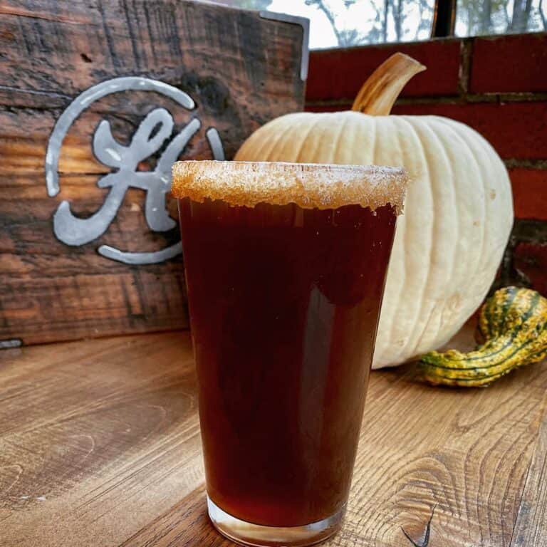 Hoodletown Brewery's Pumpkin Ale called Warlocks Grave in a pint glass with a pumpkin and gourd in the background as decoration.