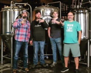 Hoodletown Brewery and Main Sail Brewing staff holding new release "Wee Heavy" Scotch Ale beer